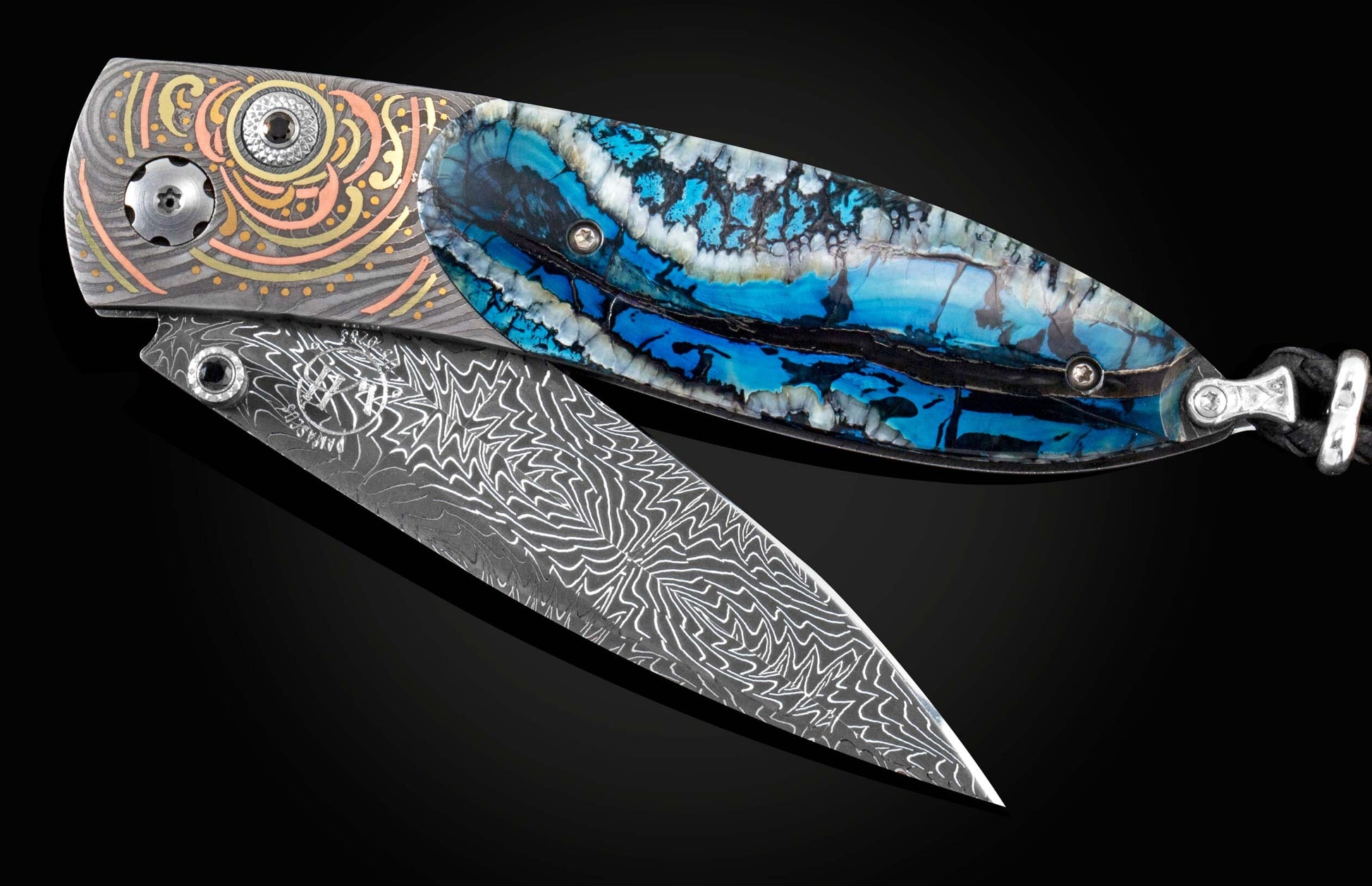 Handcrafted pocket knife from William Henry features a hand-forged Damascus frame with fine inlays of 24K & 22K yellow gold, 18K green gold and copper with fossil woolly mammoth tooth scales set with spinel gemstones and a hand-forged Damascus steel blade