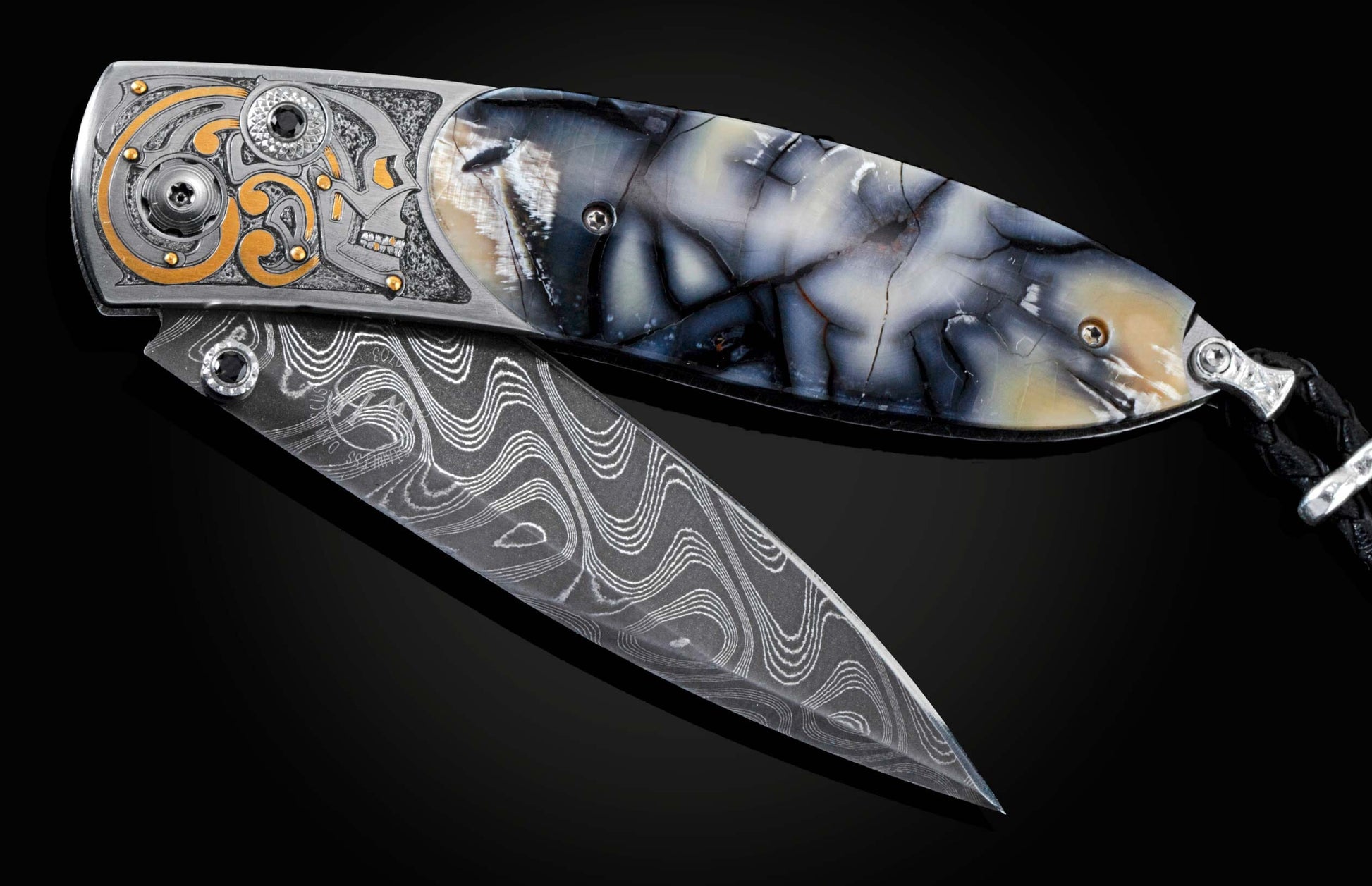Handcrafted pocket knife from William Henry features a hand-engraved skull and intricate designs with 24K gold inlaid with fossil Woolly Mammoth tusk and set with spinel gemstones. The blade is damascus steel.