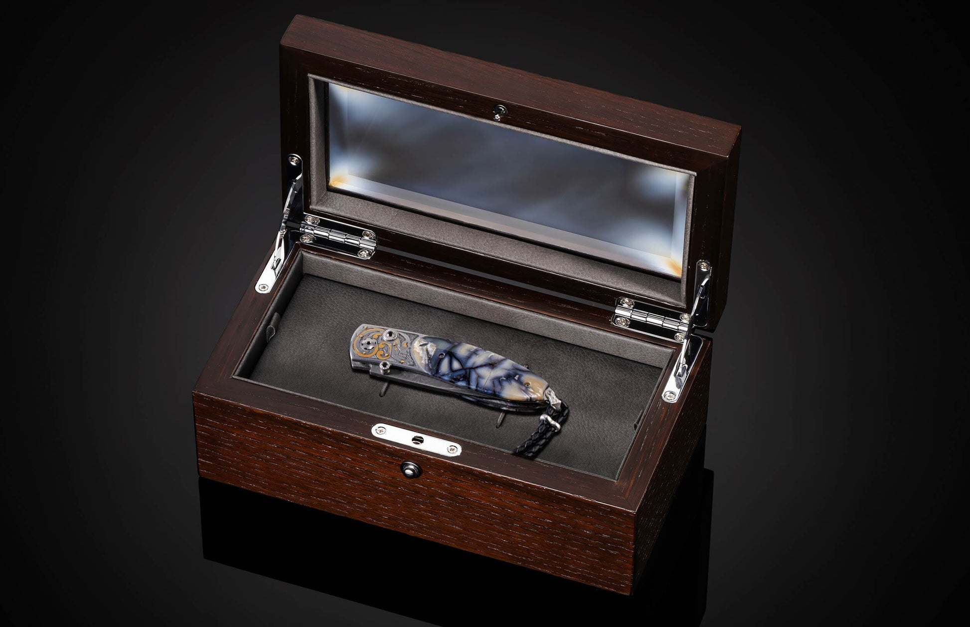 Handcrafted pocket knife from William Henry features a hand-engraved skull and intricate designs with 24K gold inlaid with fossil Woolly Mammoth tusk and set with spinel gemstones. The blade is damascus steel.