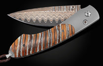 Handcrafted William Henry knife with titanium frame, inlaid with fossil Woolly Mammoth tooth, smoky quartz gems, and a hand forged Damascus steel blade.