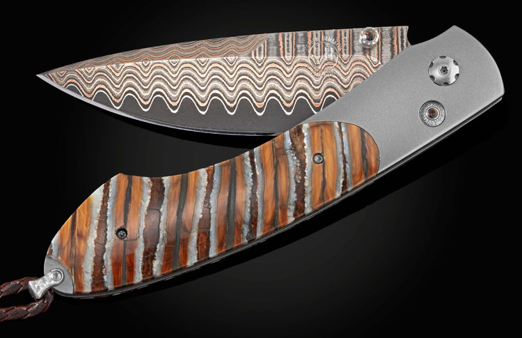 Handcrafted William Henry knife with titanium frame, inlaid with fossil Woolly Mammoth tooth, smoky quartz gems, and a hand forged Damascus steel blade.
