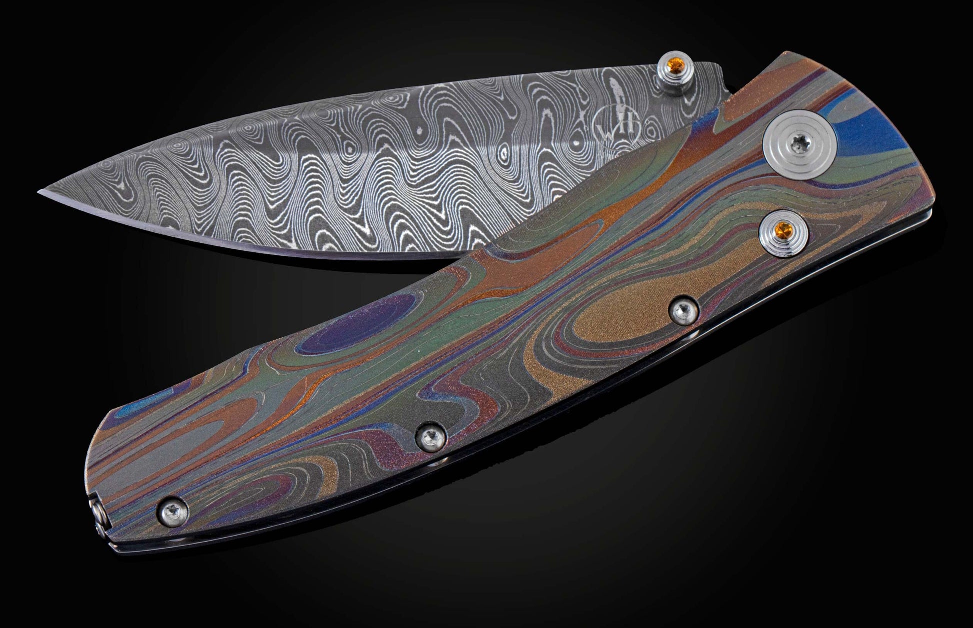 Handcrafted knife from William Henry featuring a hand forged Damascus blade and a titanium frame that is laser-engraved in a swirl of color. The button lock and thumb stud are inset with citrine gemstones. The pocket knife is shown partially open.